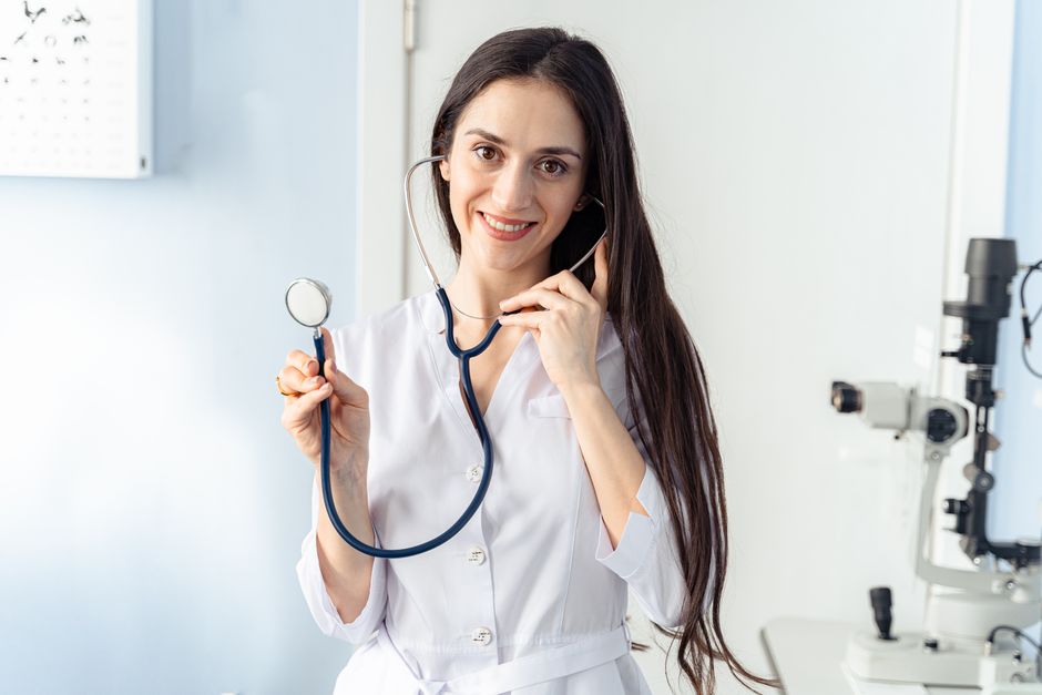 Confident female doctor holding a stethoscope while smiling in a clinic setting.